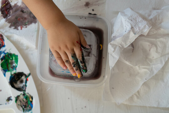 the child paints an ice cube with his finger