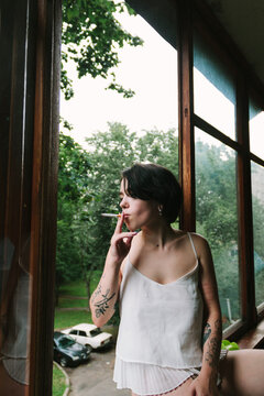 Woman with tattoos smoking while standing on the balcony
