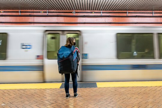 Rear view of woman carrying bag standing in front of subway train