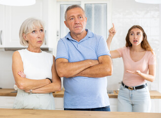 Portrait of unhappy mature father not taking after quarrel, standing in the kitchen