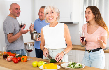 Obraz na płótnie Canvas Happy family with elderly parents preparing lunch in a modern kitchen