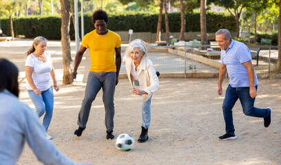 Happy multiracial men and women of various age at play of football game outdoors on a sunny day at park © JackF