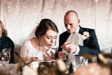 the bride and groom are fed soup during the wedding reception