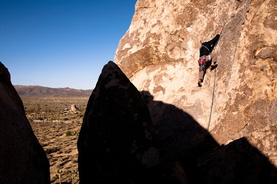 A male climber works his way up past the first bolt on Cryptic (5.8) on Headstone Rock in Joshua Tree National Park, California.