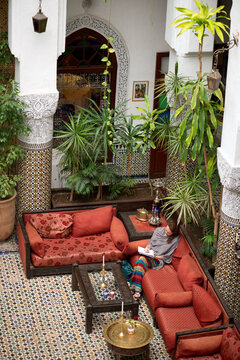 A woman relaxing and writing in her notebook in the elaborate lobby of the riad (small hotel) Dar El Ghalia in Fes el-Bali, Fes, Morocco.