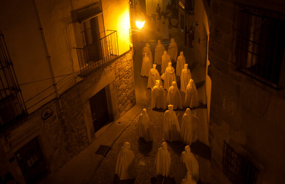 Hooded penitents dressing white capes cross an arrow street during an Easter Holy Week procession in Trujillo, Extremadura, Spain.
