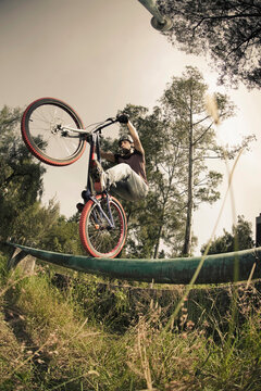 a man with a bike standing on the back wheel of his bike on a green tube during a riding session in Mexico City, DF Mexico.