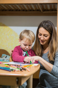 Mother assisting son to draw with coloured pencil, Munich, Germany