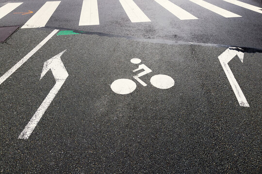 arrows, bicycle icon and zebra crossing on a city road