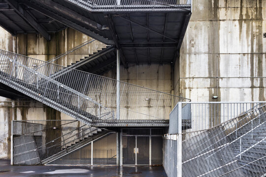 raw concrete building with industrial staircase and lattice fences