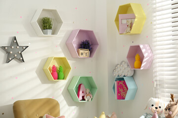 Hexagon shaped shelves on white wall in nursery. Interior design