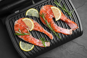Cooking salmon. Grill with fresh fish steaks, lemon and rosemary on dark table, top view