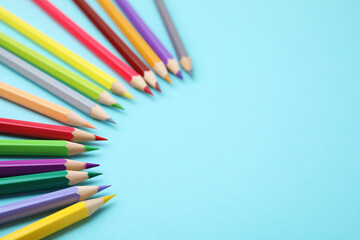 Colorful wooden pencils on light blue background, above view. Space for text