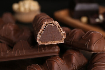Heap of tasty chocolate bars on blurred background, closeup view