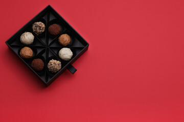 Box of tasty chocolate candies on red background, top view. Space for text