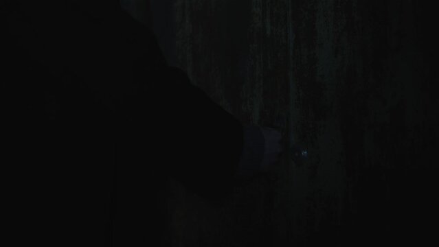 Old garage with blue light. Atmosphere dark place full of smoke. Strang and mystery man in black coat and black hat is walking 