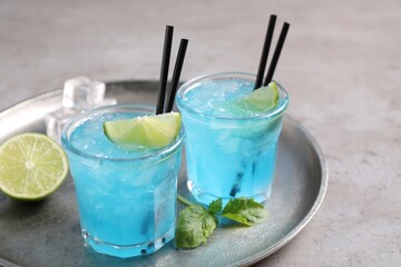 Tasty fresh light blue drink with lime on grey table