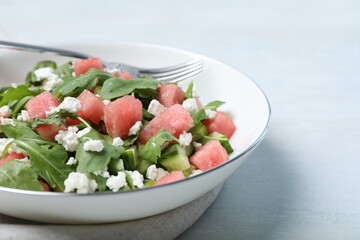 Delicious salad with watermelon, cucumber, arugula and feta cheese on white table, closeup. Space for text