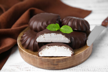 Delicious chocolate covered marshmallows with mint on white wooden table