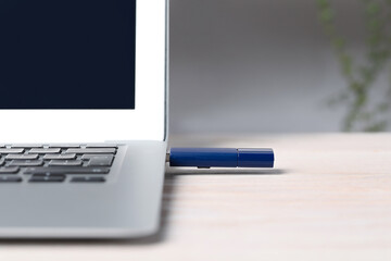Usb flash drive attached into laptop on white wooden table, closeup. Space for text