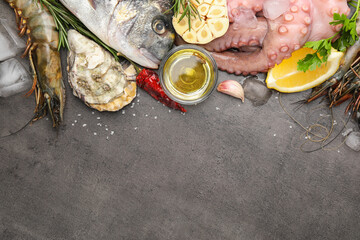 Flat lay composition with fresh raw dorado fish and different seafood on grey table. Space for text