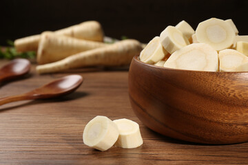 Fresh ripe parsnip in bowl on wooden table. Space for text
