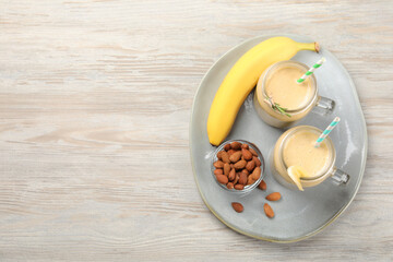 Tasty banana smoothie and ingredients on white wooden table, flat lay. Space for text