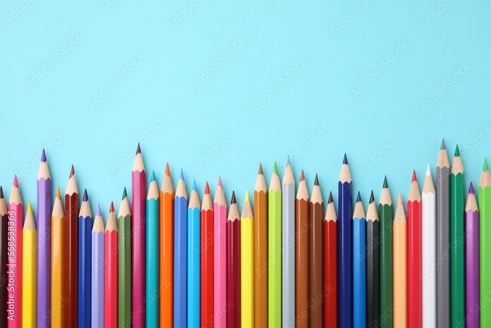 Poster Colorful wooden pencils on light blue background, flat lay. Space for text