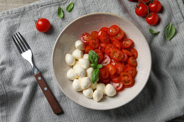 Delicious mozzarella balls, tomatoes and fork on table, flat lay