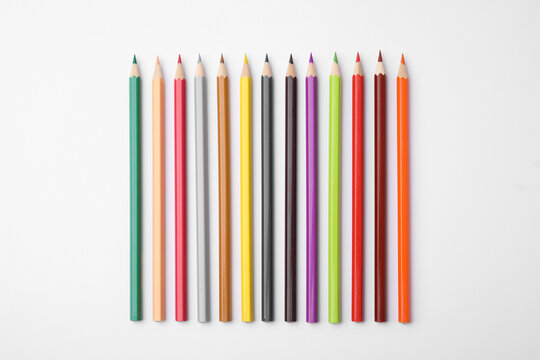Colorful wooden pencils on white background, flat lay