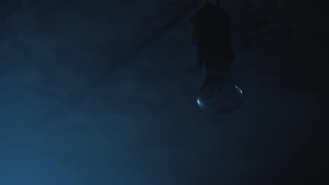 Old garage has lamp with blue light. Atmosphere dark place full of smoke.