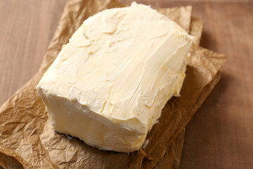 Parchment with tasty homemade butter on wooden table