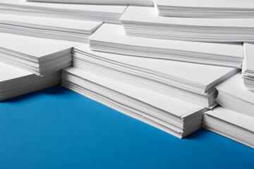 Many stacks of paper sheets on blue background, closeup
