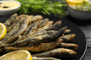 Plate with delicious fried anchovies and slices of lemon, closeup