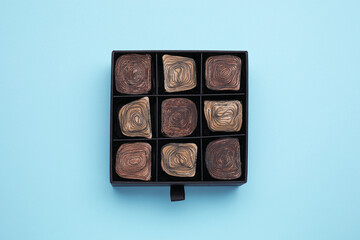Box of tasty chocolate candies on light blue background, top view