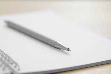 Open notebook with pen on wooden table, closeup