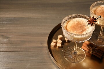 Delicious eggnog with cinnamon and anise on wooden table. Space for text