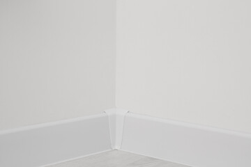 Corner of white wall with baseboard indoors