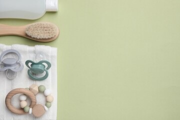 Flat lay composition with pacifiers and other baby stuff on pale green background. Space for text
