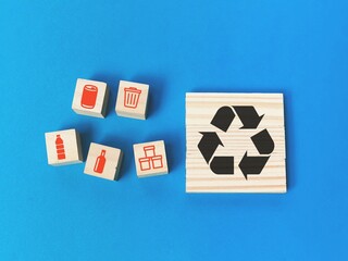 Recycle concept with icons on wooden blocks against blue background.