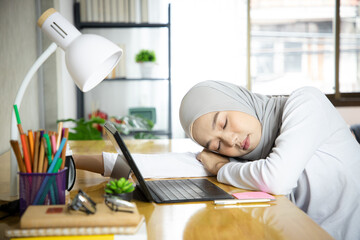 Muslim businesswoman clearing sales target and sleep less on table at working space. Asian woman in...