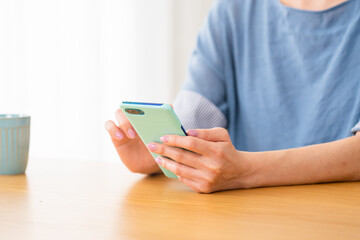 車椅子に座りながらスマートフォンを操作する若い女性　多様性社会イメージ