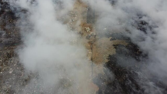 Aerial top down view excavator try to stop the fire from spread at landfill dump site
