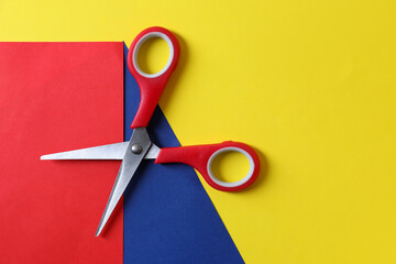 Red scissors and color sheets of paper on yellow background, top view. Space for text - obrazy, fototapety, plakaty