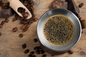 Turkish coffee pot with hot drink and beans on wooden table, flat lay. Space for text