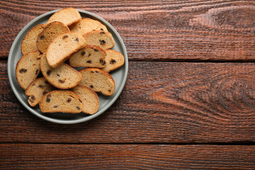 Plate of sweet hard chuck crackers with raisins on wooden table, top view. Space for text