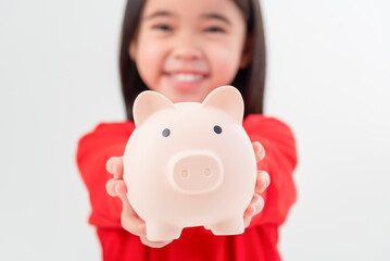 Little Asian girl saving money in a piggy bank, learning about saving, Kid save money for future education. Money, finances, insurance, and people concept