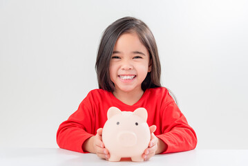 Little Asian girl saving money in a piggy bank, learning about saving, Kid save money for future education. Money, finances, insurance, and people concept