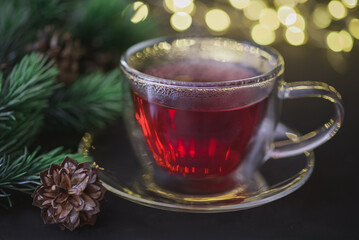 Hot red karkade tea in transparent cup against blurry Christmas lights