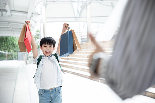 Big sale surprise. Handsome attractive boy smiling shopping in the city. Photo of young cute boy smiling positive cheerful and hold shopping bags of mid year sale show father.